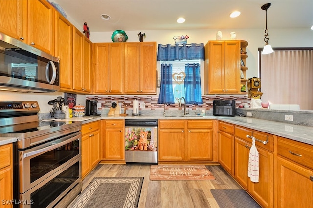 kitchen featuring appliances with stainless steel finishes, sink, pendant lighting, and light wood-type flooring