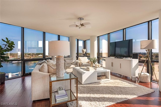 living room with expansive windows, ceiling fan, dark hardwood / wood-style flooring, and a water view