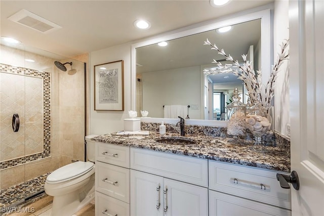 bathroom featuring vanity, toilet, tile patterned flooring, and a tile shower