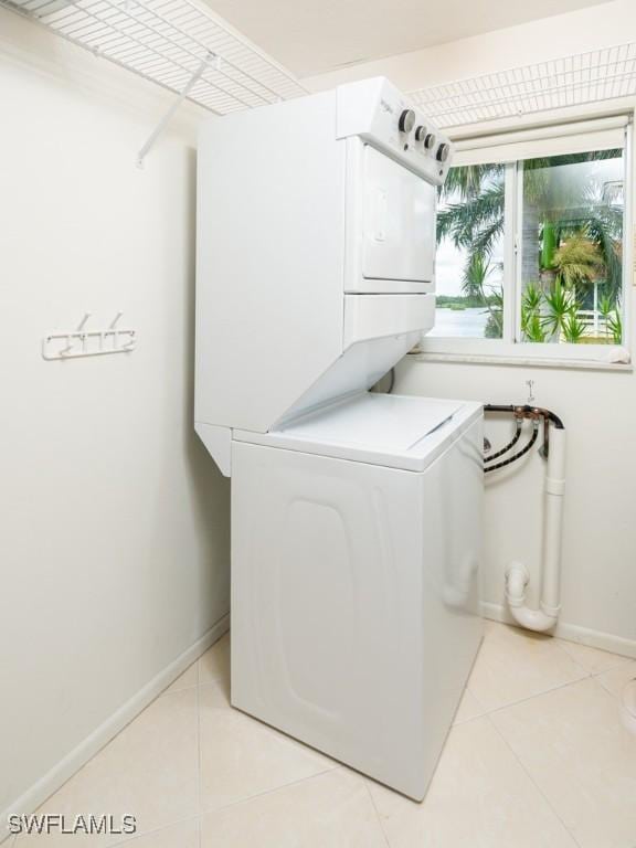 laundry room with light tile patterned floors and stacked washing maching and dryer