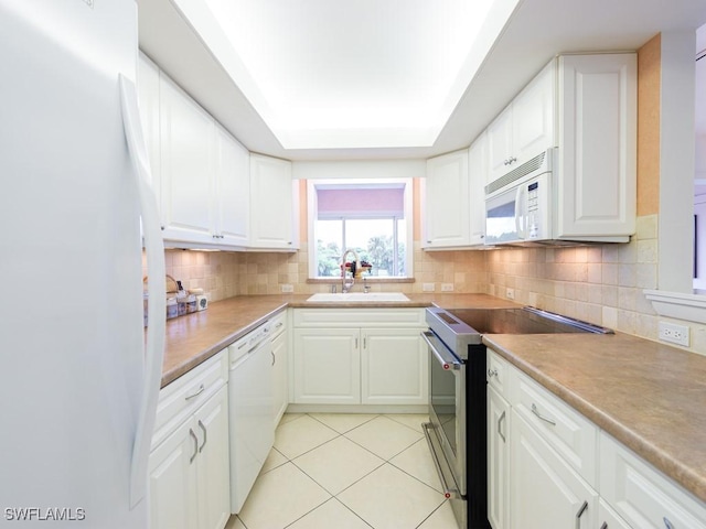 kitchen featuring sink, light tile patterned floors, white cabinets, and white appliances