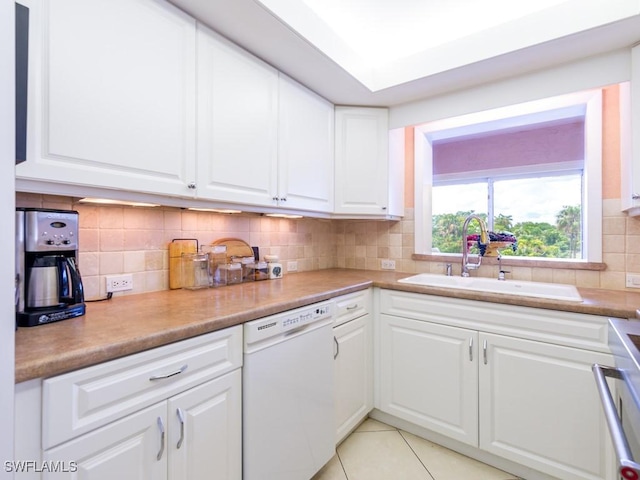 kitchen with tasteful backsplash, white cabinetry, sink, light tile patterned floors, and white dishwasher