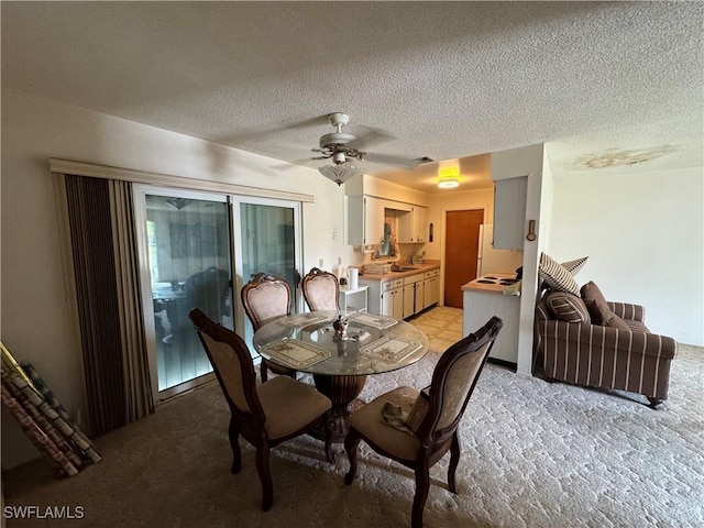 dining space featuring ceiling fan, light colored carpet, a textured ceiling, and sink