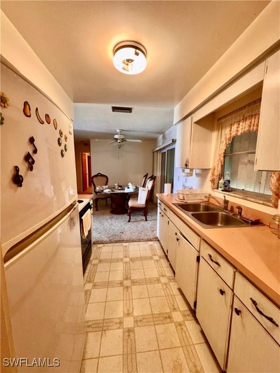 kitchen featuring ceiling fan, sink, and white fridge