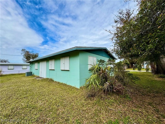 view of side of property with central AC and a yard