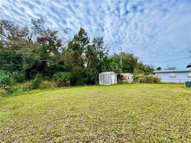 view of yard with central air condition unit and a storage shed