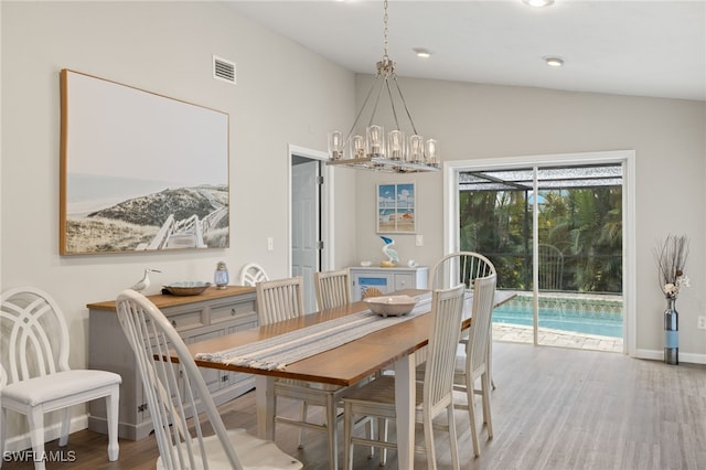 dining room with an inviting chandelier, wood-type flooring, and vaulted ceiling