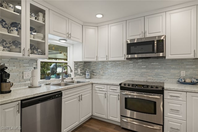 kitchen with appliances with stainless steel finishes, tasteful backsplash, white cabinetry, sink, and light stone countertops