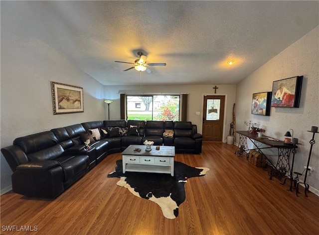 living room featuring hardwood / wood-style floors, vaulted ceiling, a textured ceiling, and ceiling fan