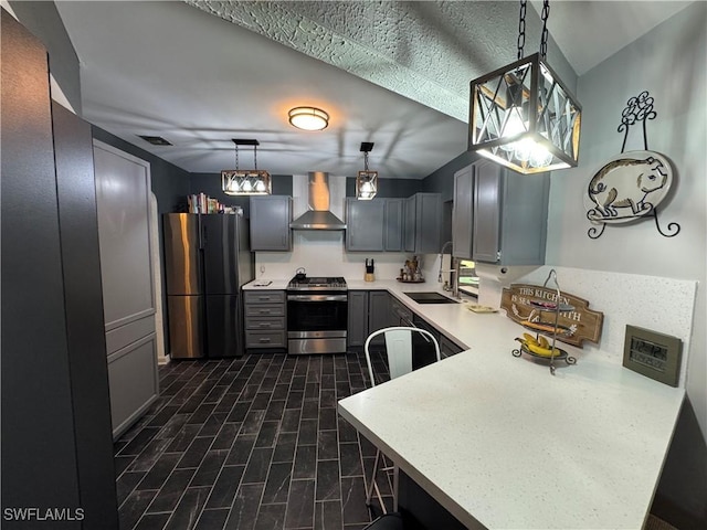 kitchen featuring wall chimney exhaust hood, sink, hanging light fixtures, kitchen peninsula, and stainless steel appliances