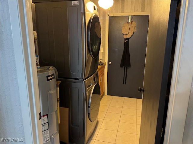 clothes washing area featuring stacked washer and clothes dryer, electric water heater, and light tile patterned floors