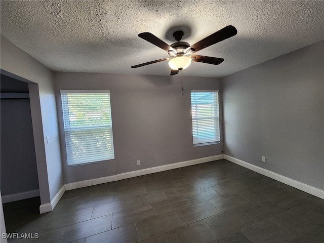 unfurnished bedroom featuring ceiling fan, multiple windows, and a textured ceiling