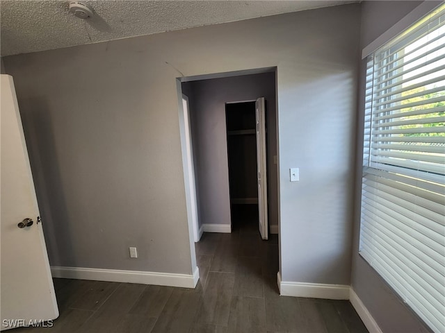 unfurnished room with dark wood-type flooring and a textured ceiling