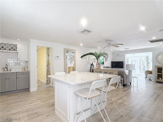 kitchen featuring a kitchen breakfast bar, sink, white cabinets, a kitchen island, and decorative backsplash