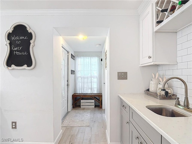 kitchen featuring sink, light stone counters, light hardwood / wood-style floors, and decorative backsplash