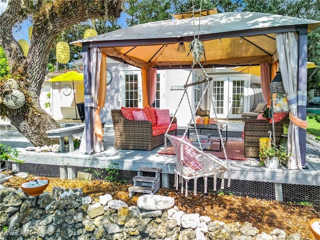 exterior space featuring french doors, a gazebo, a wooden deck, and an outdoor hangout area