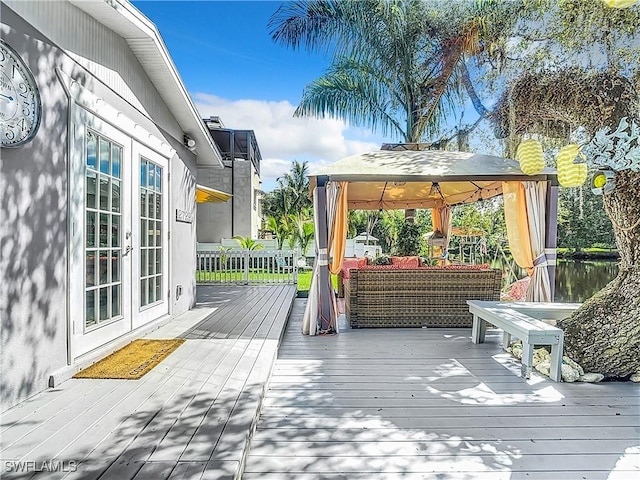 wooden terrace with an outdoor living space, a gazebo, and french doors