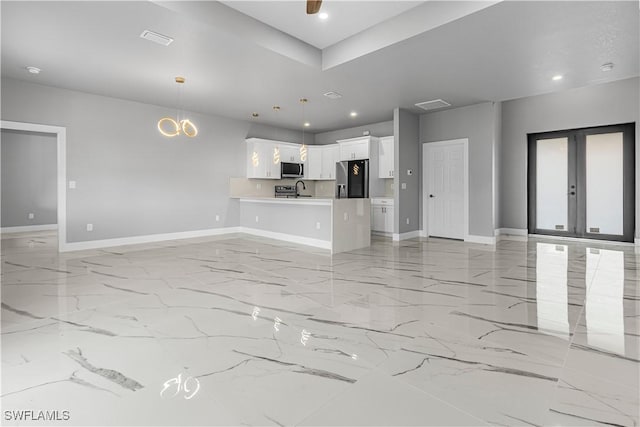 unfurnished living room featuring french doors, sink, and ceiling fan with notable chandelier