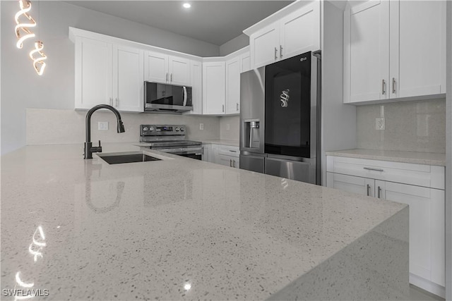 kitchen with light stone counters, sink, white cabinets, and appliances with stainless steel finishes