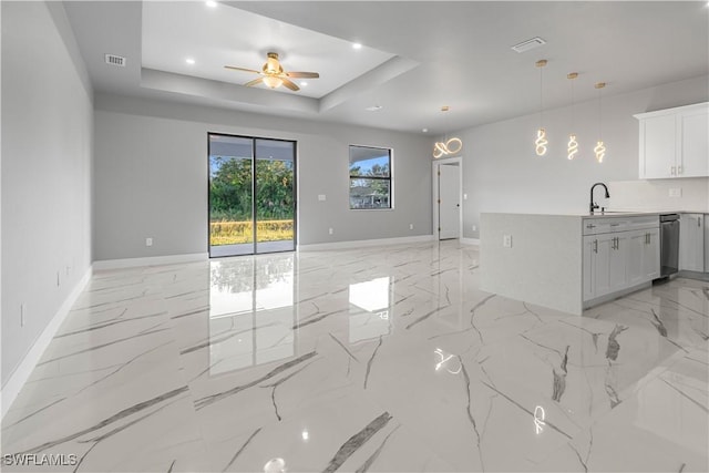 unfurnished living room featuring ceiling fan, a tray ceiling, and sink