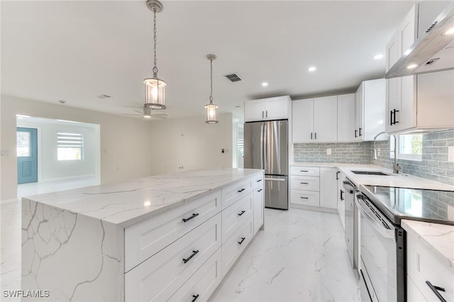 kitchen with a center island, white cabinetry, stainless steel appliances, sink, and light stone counters