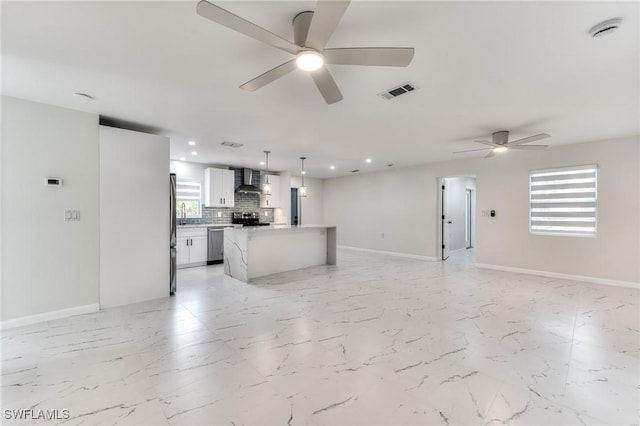 kitchen with pendant lighting, white cabinets, a center island, wall chimney exhaust hood, and stainless steel appliances