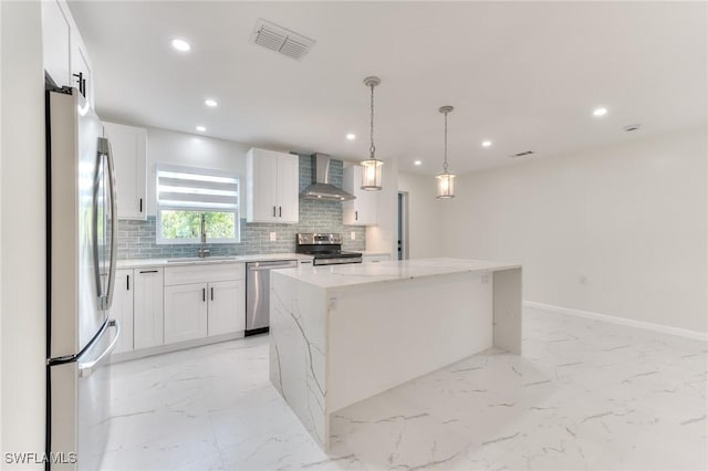 kitchen with a center island, white cabinetry, stainless steel appliances, light stone counters, and wall chimney exhaust hood