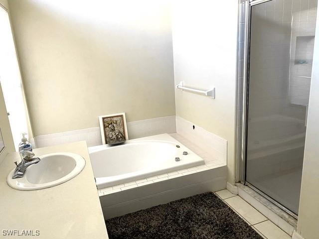 bathroom with tile patterned flooring, separate shower and tub, and sink