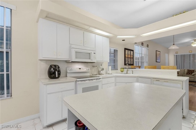 kitchen featuring white appliances, a peninsula, white cabinetry, light countertops, and decorative backsplash