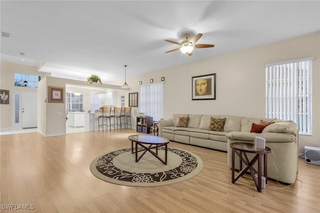 living area featuring visible vents, ceiling fan, wood finished floors, and baseboards