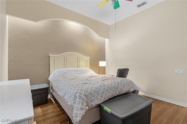 bedroom featuring wood finished floors, baseboards, a ceiling fan, and visible vents