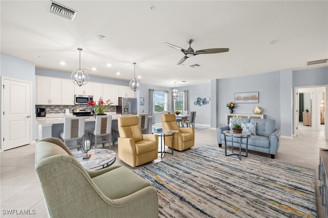 tiled living room featuring ceiling fan with notable chandelier