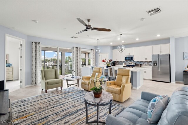 living room featuring light tile patterned floors and ceiling fan with notable chandelier