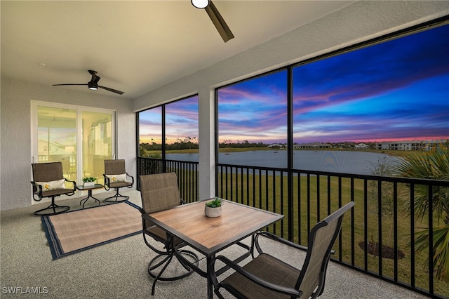 sunroom with a water view and ceiling fan