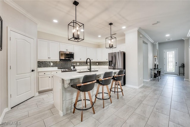 kitchen with white cabinetry, an island with sink, sink, hanging light fixtures, and stainless steel appliances