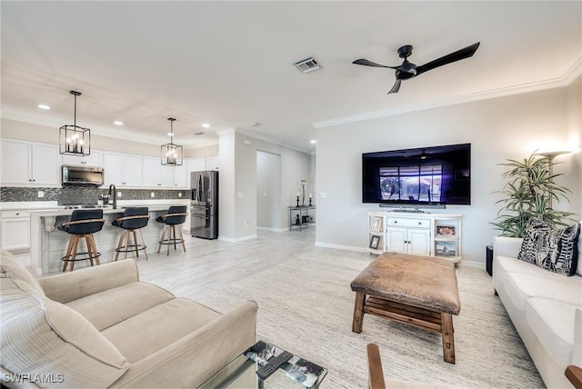 living room featuring crown molding, ceiling fan, and sink