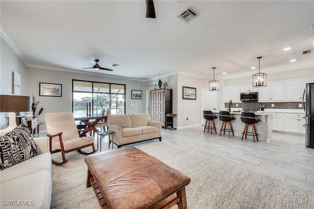 living room with sink, light hardwood / wood-style flooring, ornamental molding, and ceiling fan