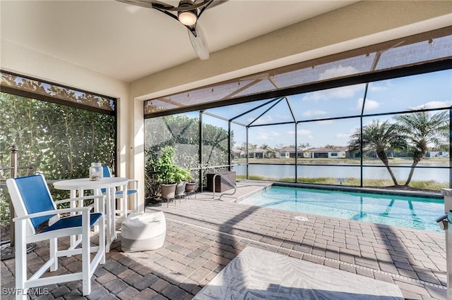 view of swimming pool featuring a lanai, a patio area, ceiling fan, and a water view