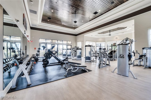 gym featuring wood-type flooring, ornamental molding, a raised ceiling, and wooden ceiling