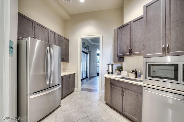 kitchen with appliances with stainless steel finishes, sink, and dark brown cabinetry