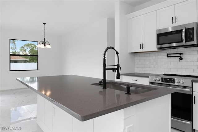 kitchen featuring hanging light fixtures, sink, white cabinets, an island with sink, and stainless steel appliances