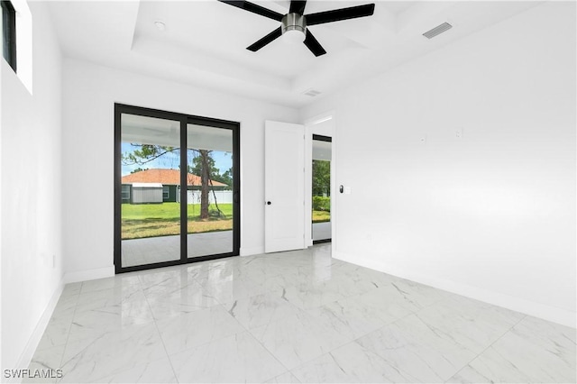 unfurnished room with ceiling fan and a raised ceiling