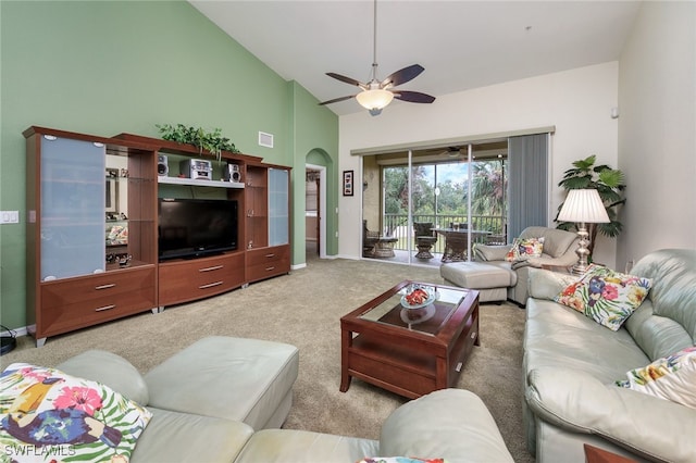 carpeted living room with ceiling fan and high vaulted ceiling