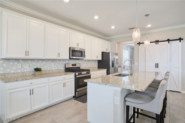 kitchen featuring white cabinetry, sink, stainless steel appliances, and a center island with sink