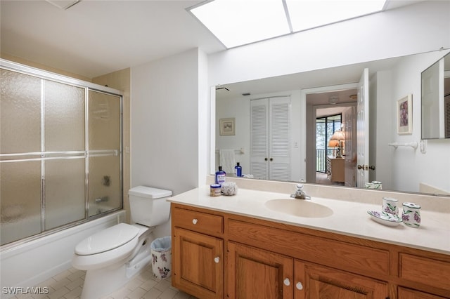 full bathroom with tile patterned flooring, vanity, a skylight, bath / shower combo with glass door, and toilet