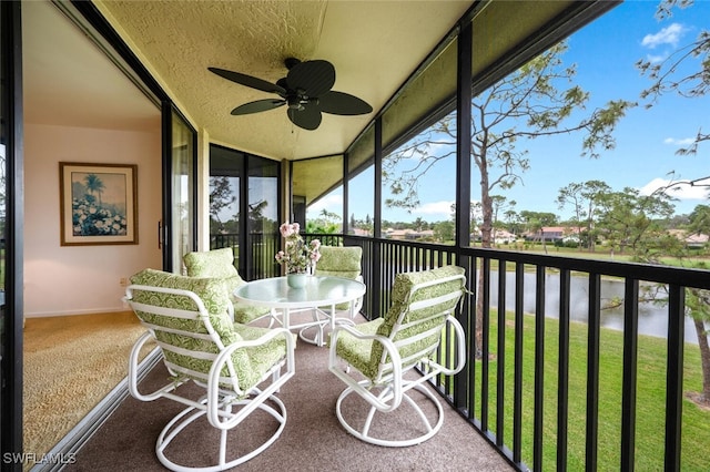 sunroom with a water view and ceiling fan