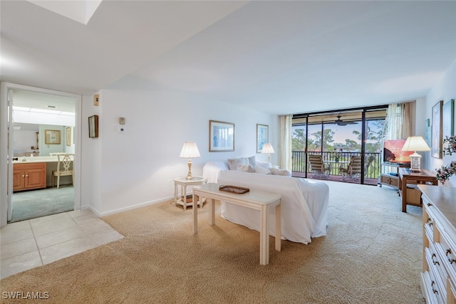 carpeted bedroom with a wall of windows, access to exterior, and ensuite bath