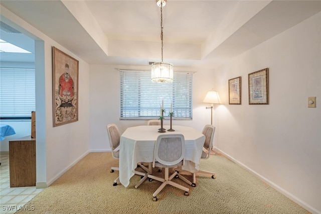 dining space featuring a raised ceiling and light colored carpet