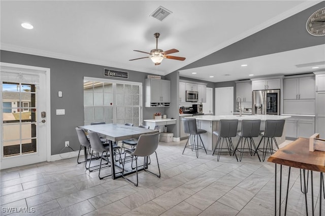 dining room with sink, vaulted ceiling, ceiling fan, and crown molding