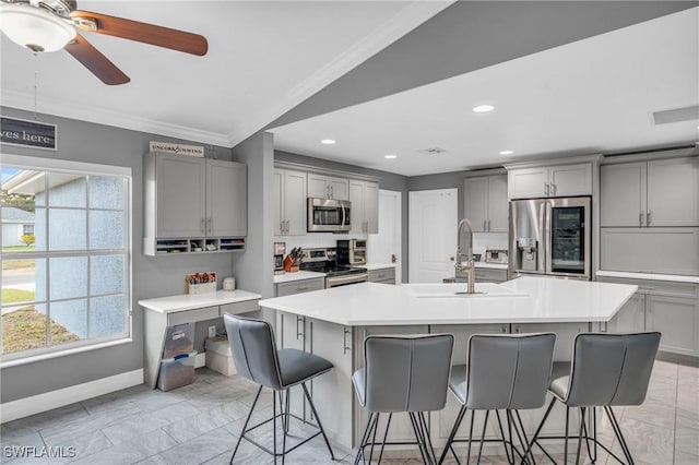 kitchen featuring appliances with stainless steel finishes, an island with sink, sink, vaulted ceiling, and a breakfast bar area